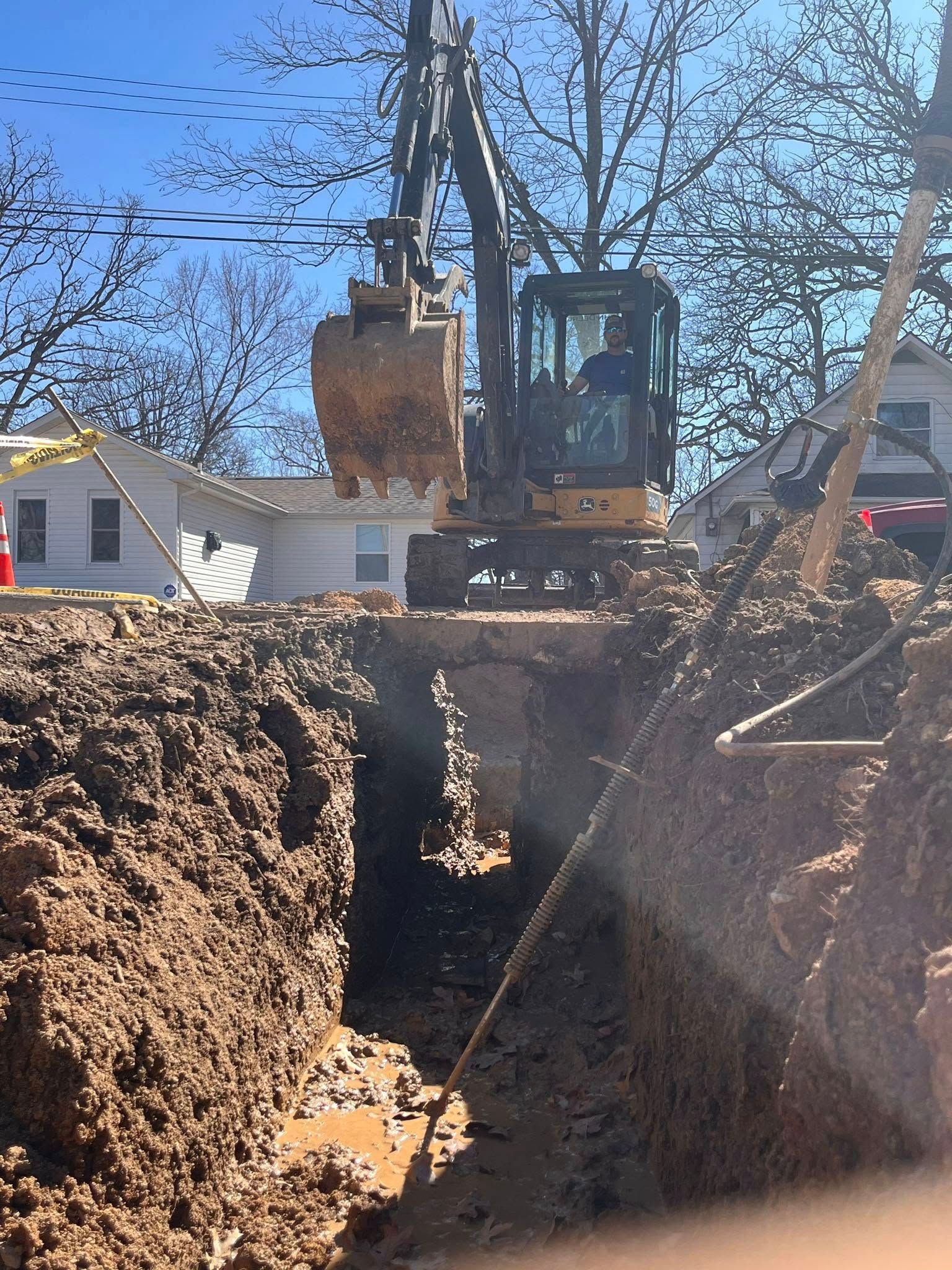 Woman in straw hat smiles, holding wine glass near a lake.