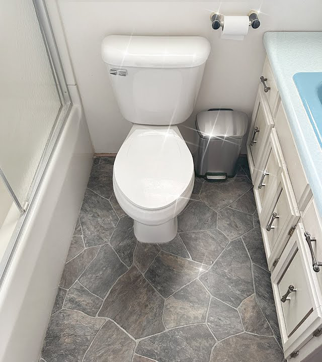 A bathroom with a toilet , sink and trash can