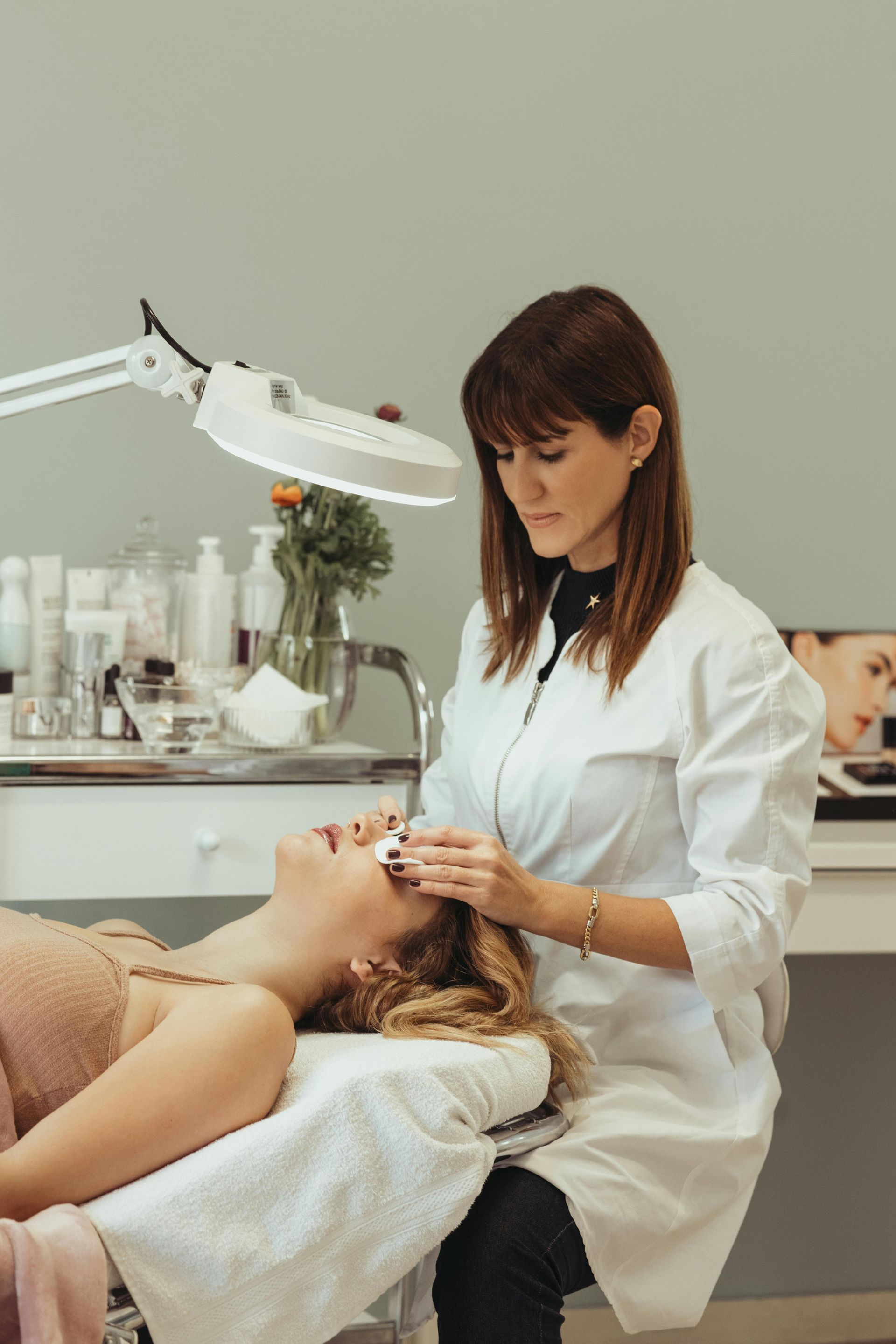 esthetician working on a client in a white room with all white equipment
