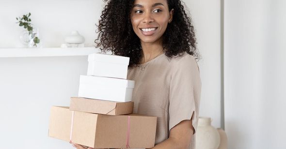 A woman is holding a stack of boxes in her hands.