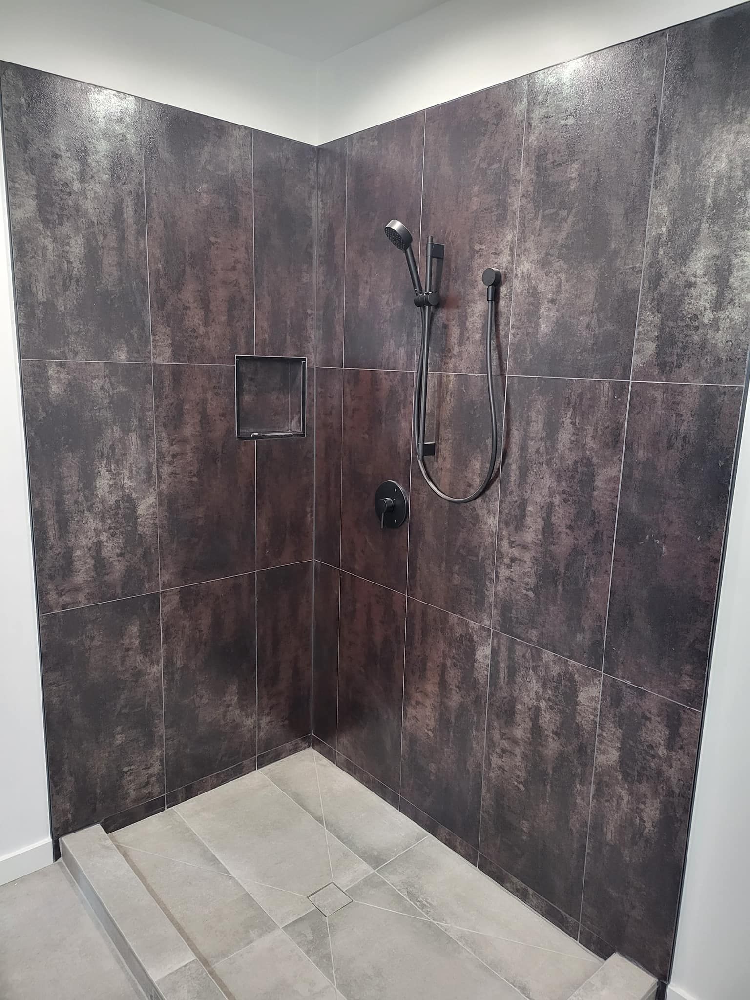 A bathroom with a walk in shower and a black shower head.
