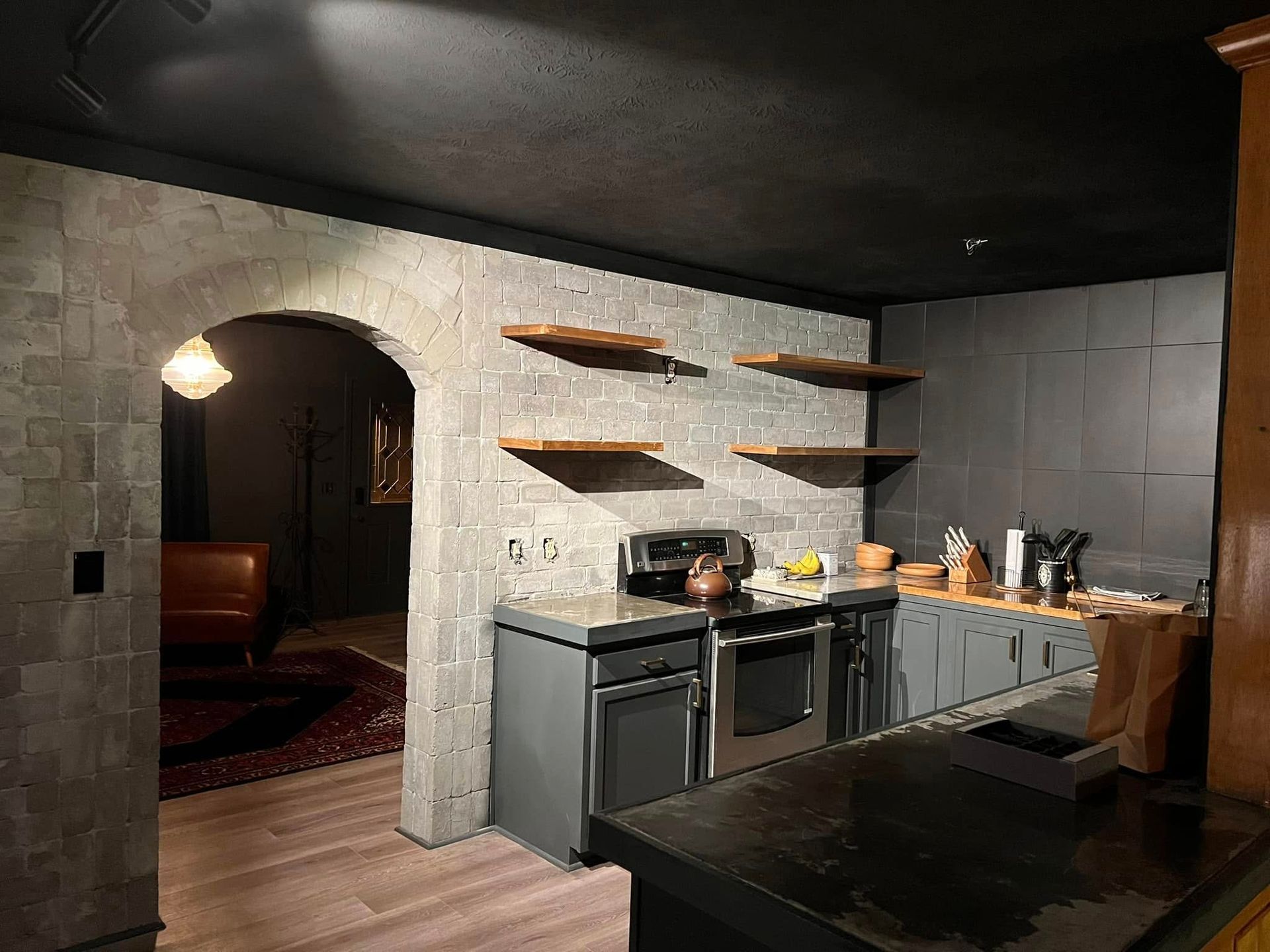 A kitchen with a stove , oven , sink , and shelves.