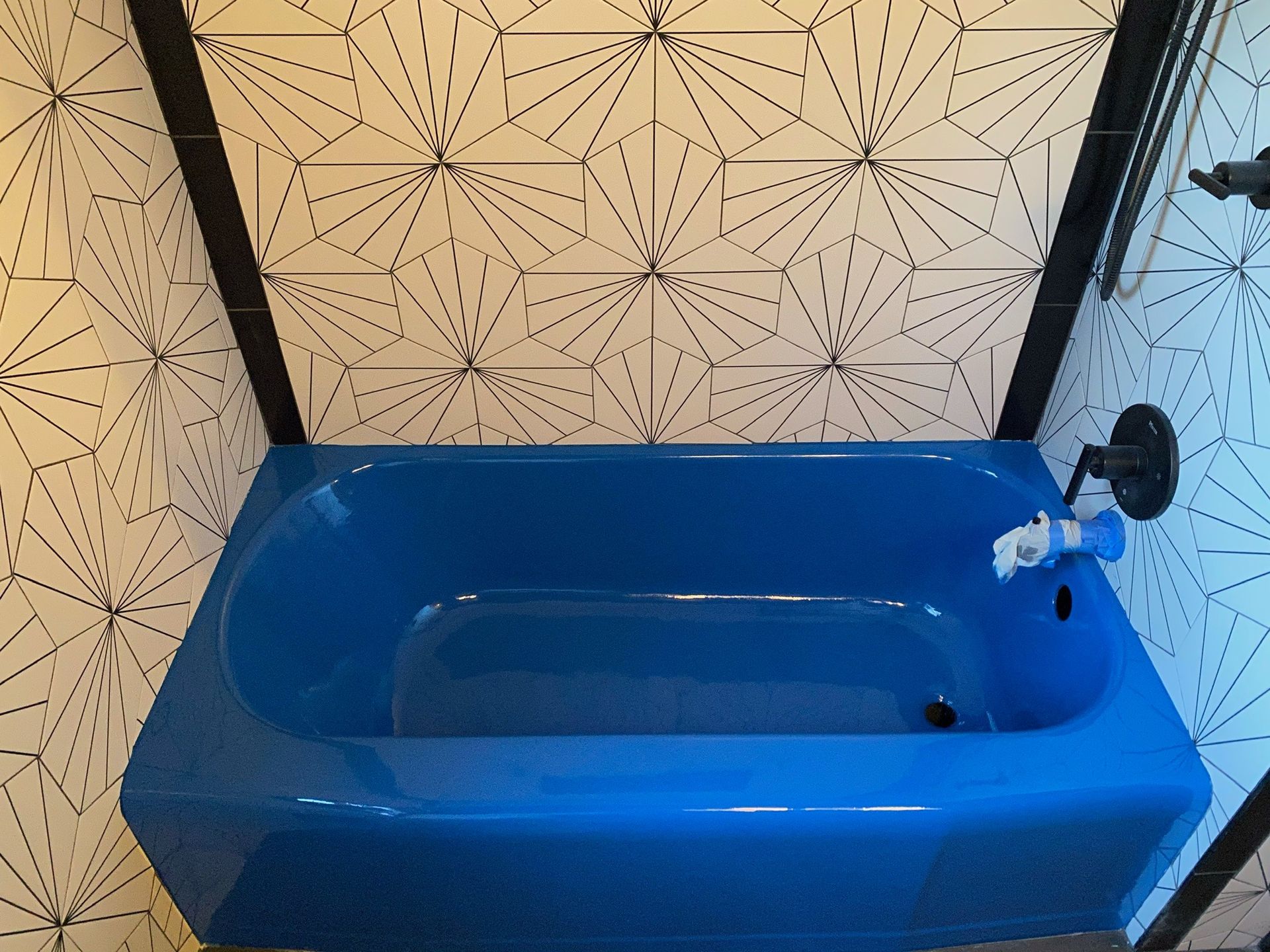 A blue bathtub in a bathroom with black and white tiles