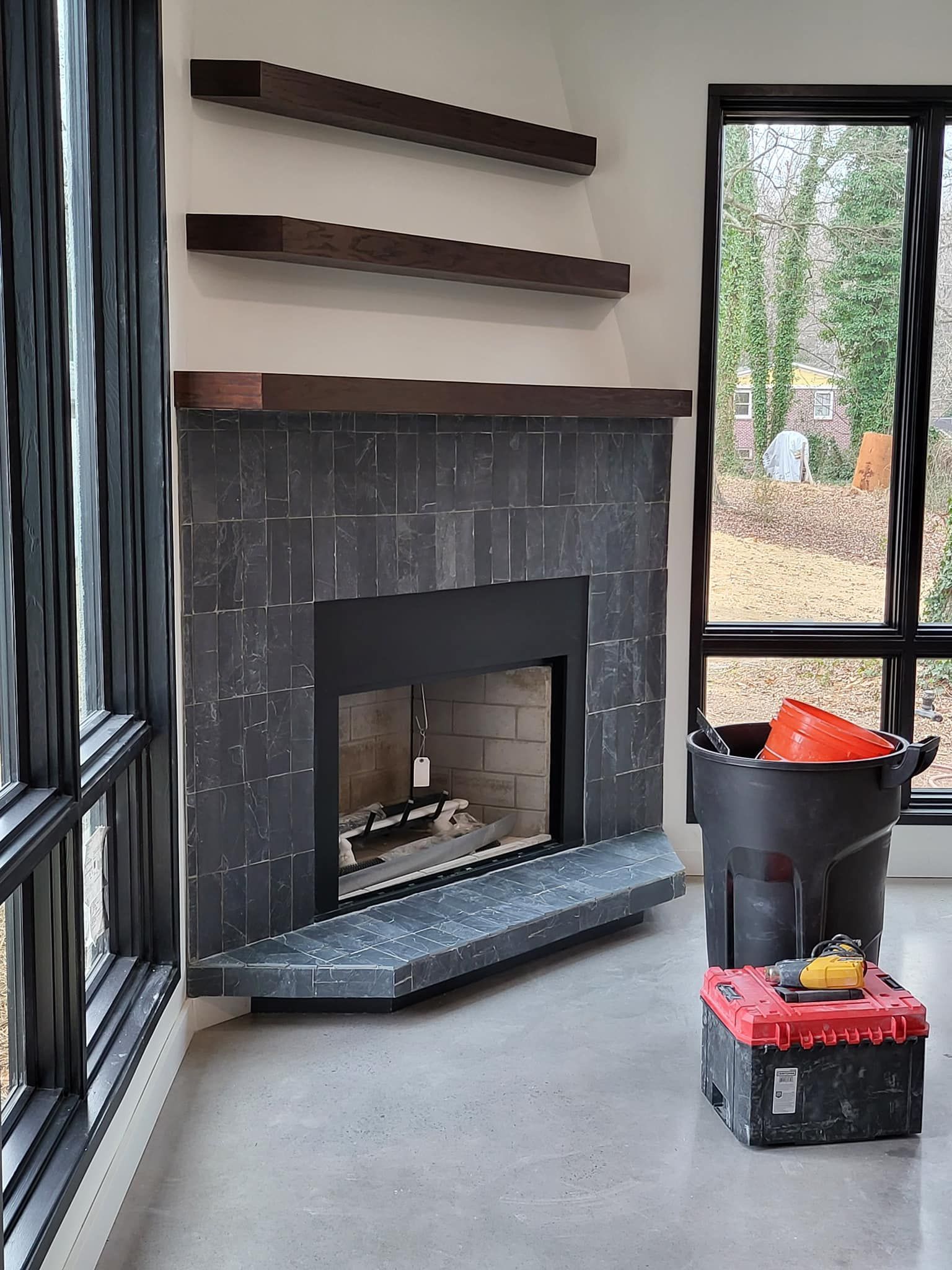 A living room with a fireplace , shelves , and a window.