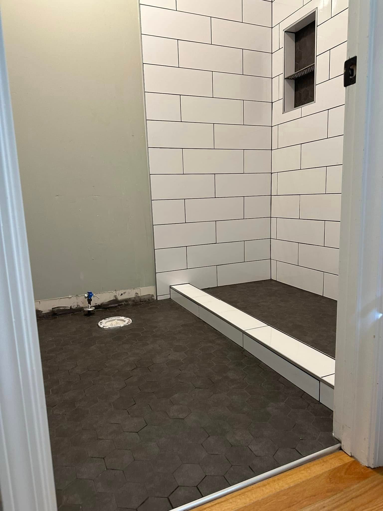 A bathroom with white tiles on the walls and black tiles on the floor.