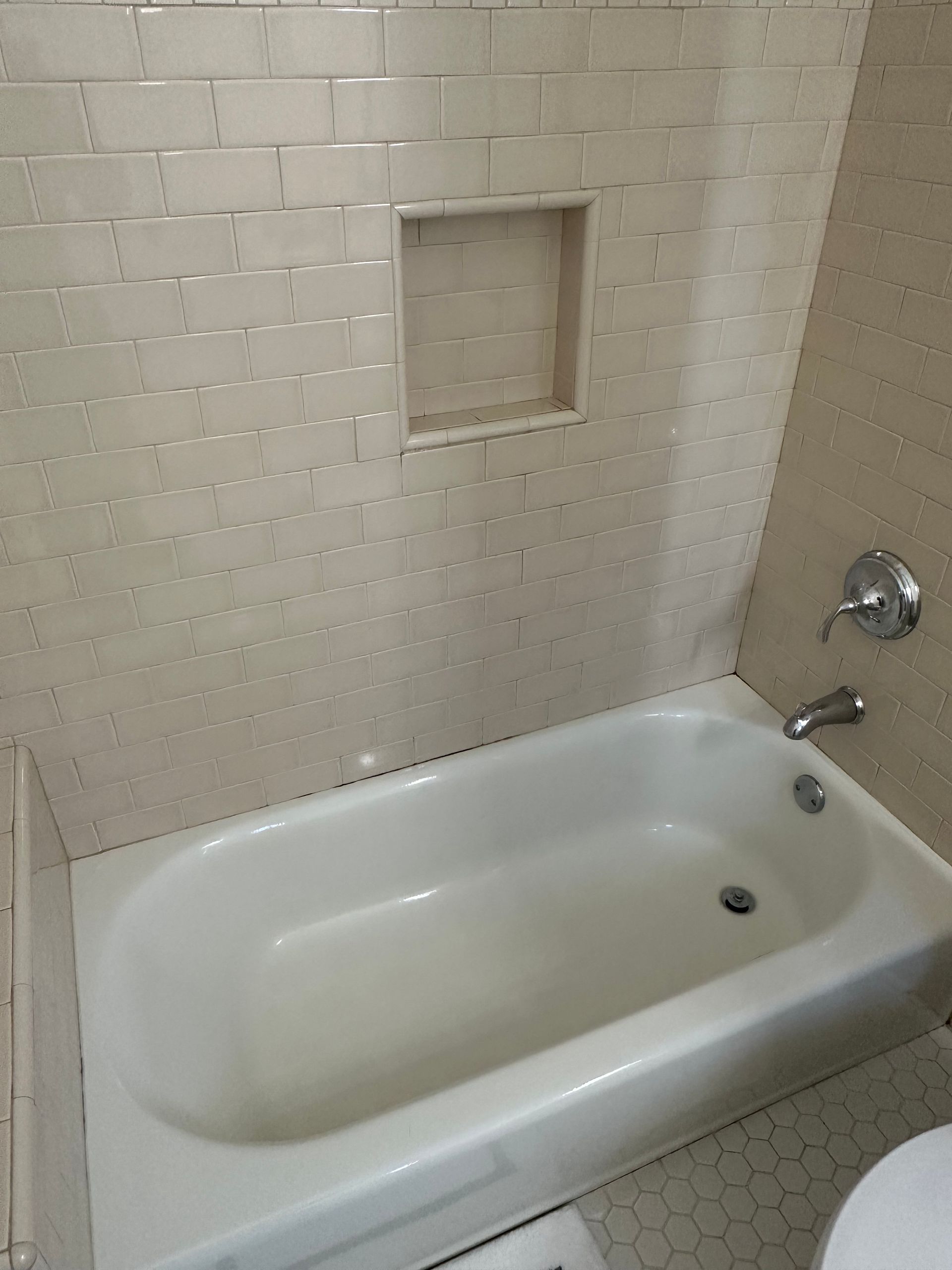 A white bathtub is in a bathroom next to a toilet.