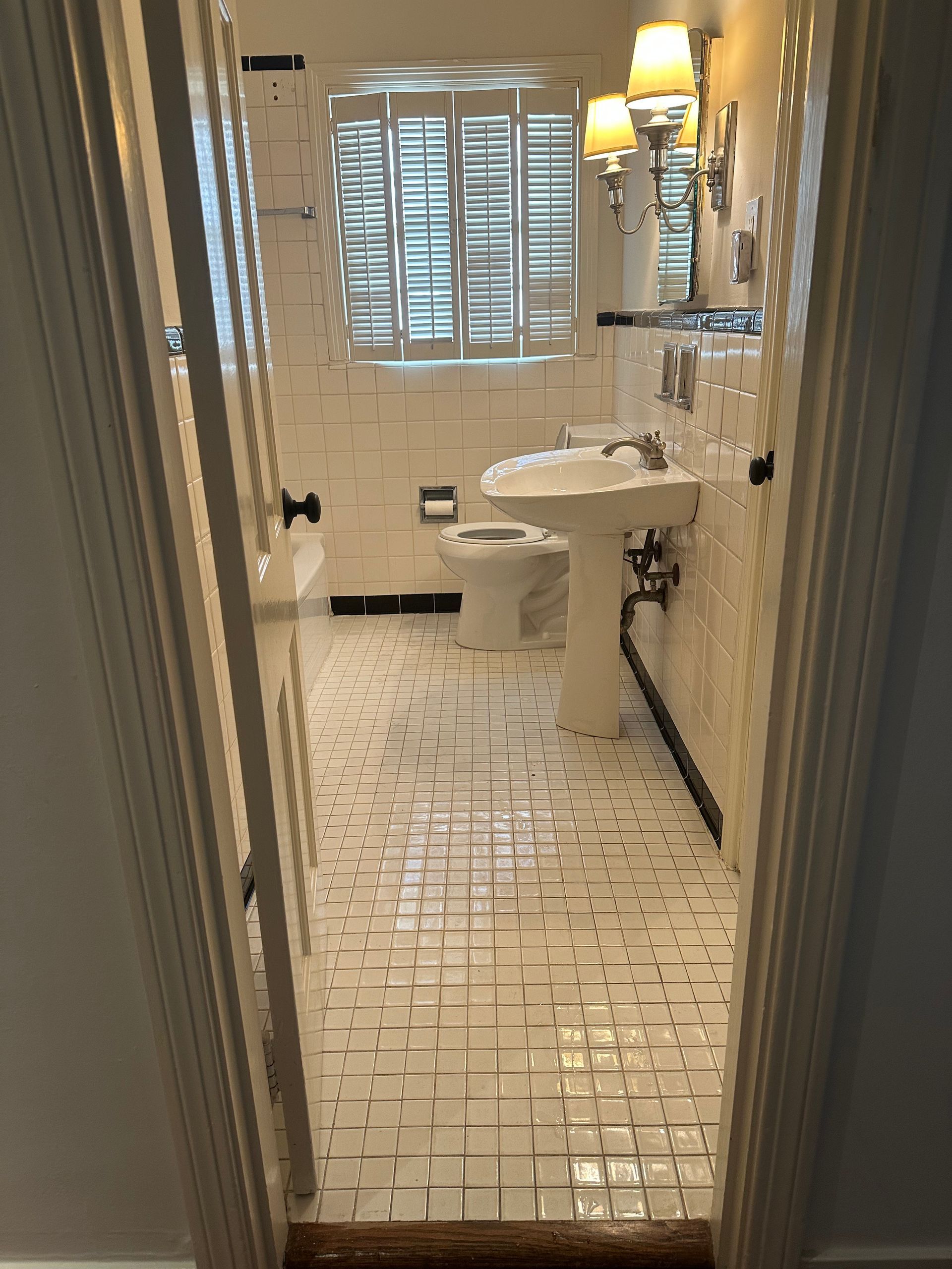 A bathroom with white tiles and a toilet and sink