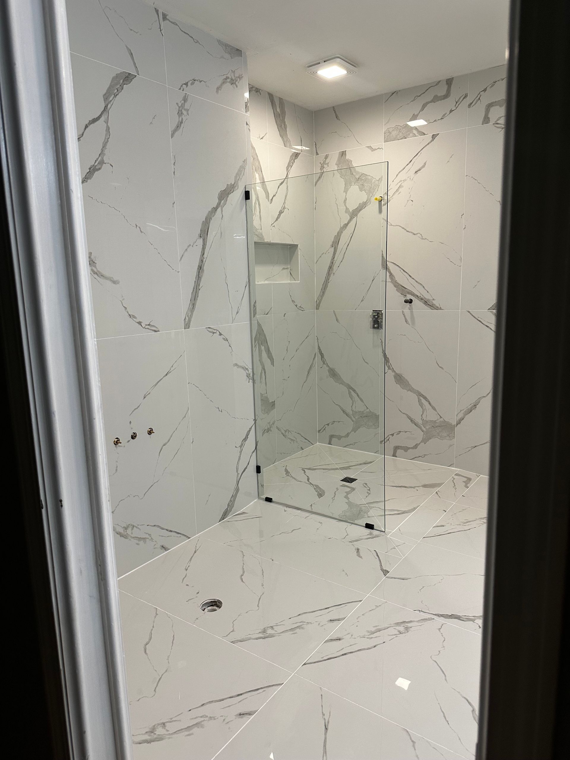 A bathroom with a toilet , sink , mirror and door.