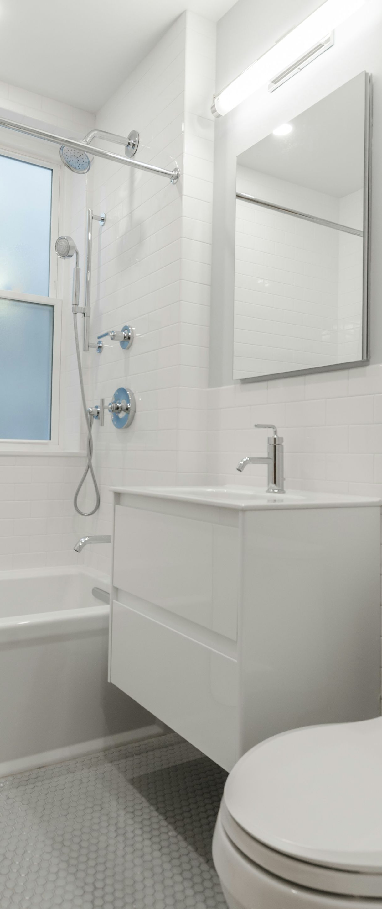Bright white bathroom with tub, shower, sink vanity, mirror, and toilet.