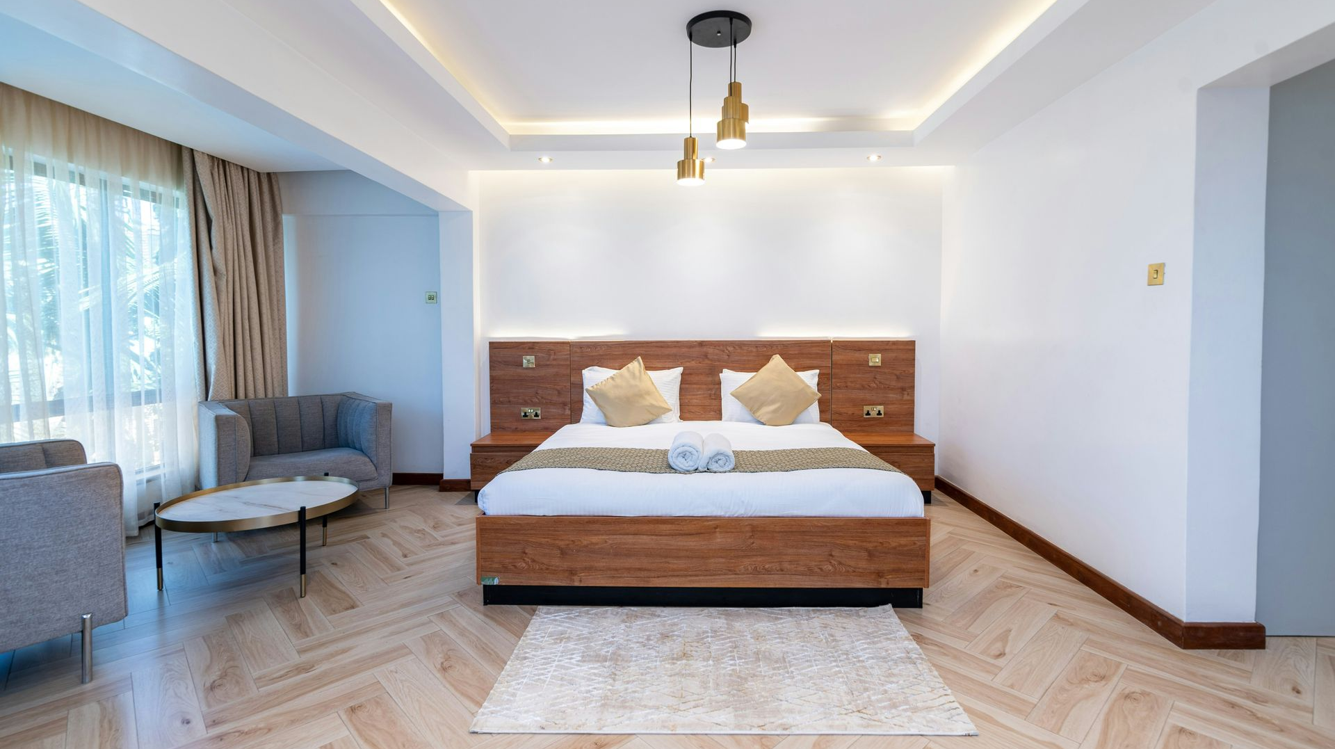 Luxurious hotel room with a wooden bed, seating area, and hardwood floors.