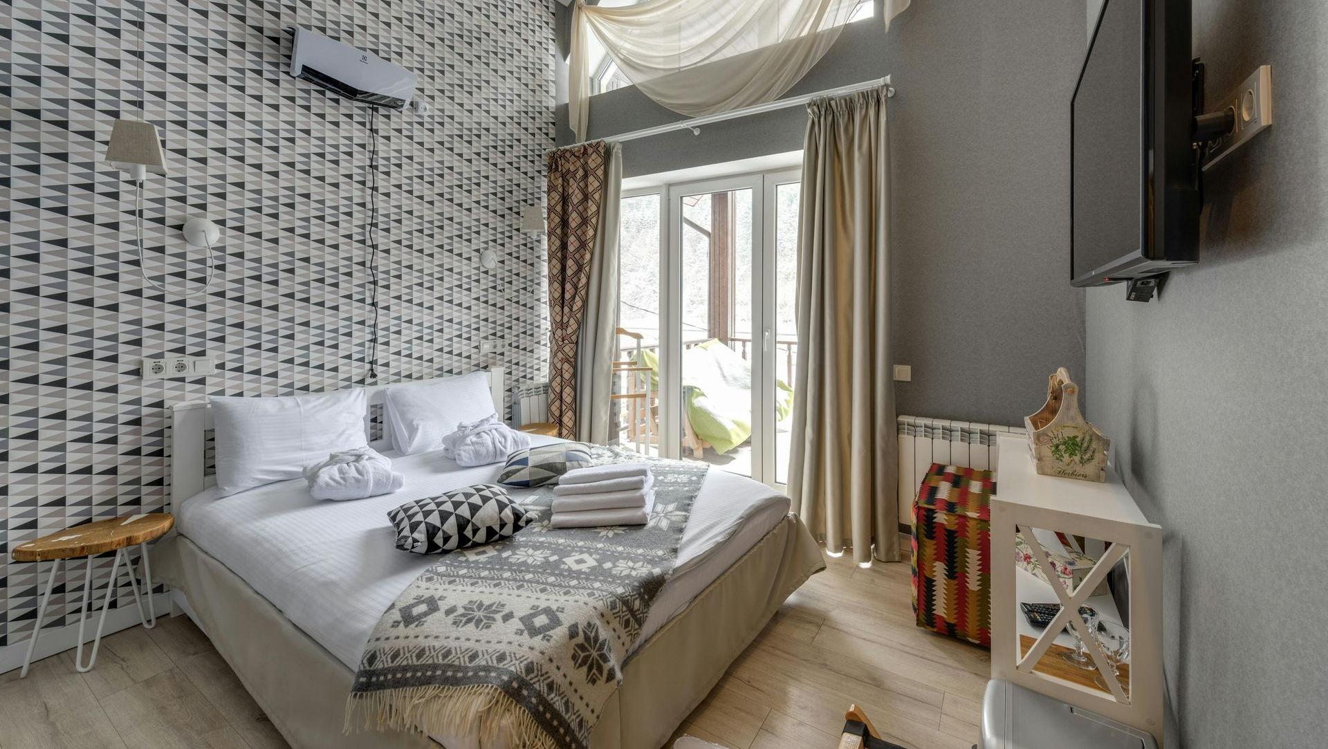 Bedroom with patterned wallpaper, bed, TV, and balcony door.