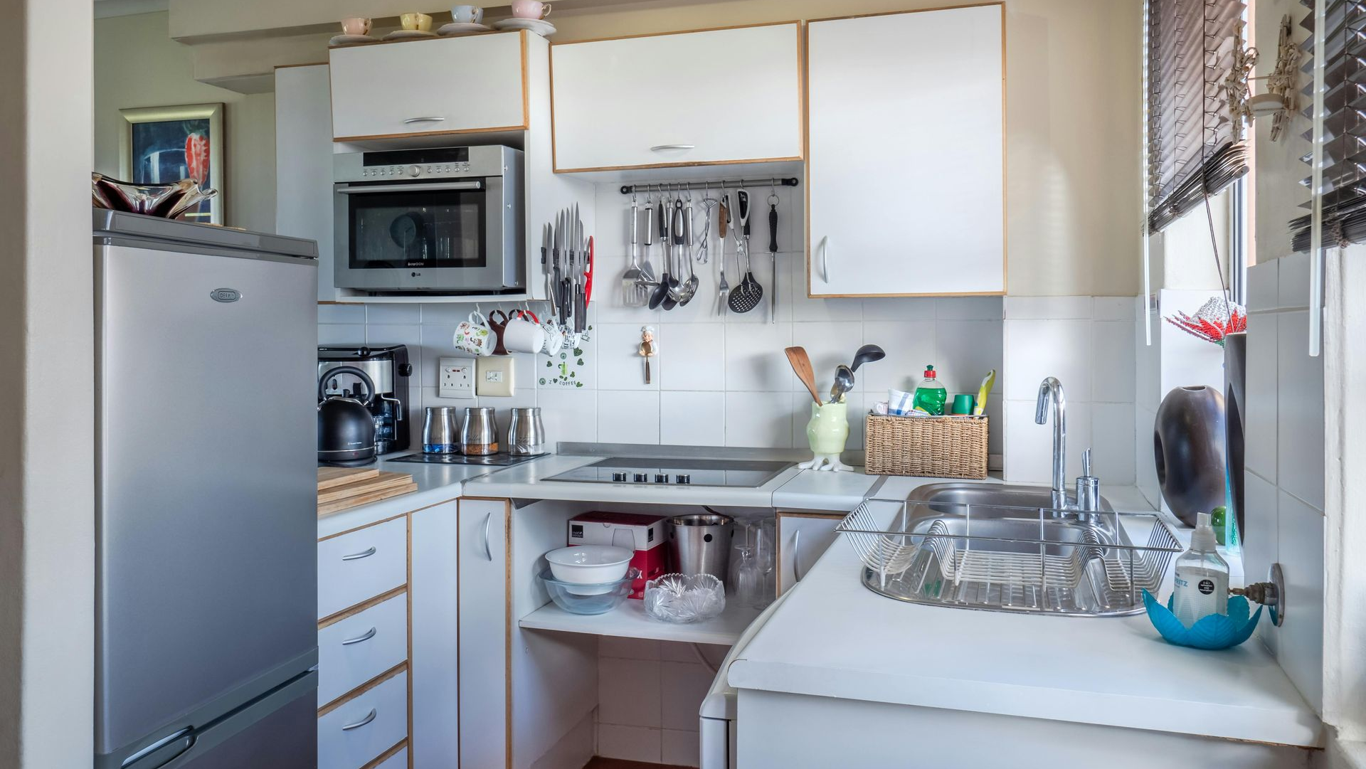 Small kitchen with white cabinets, appliances, and sink. Window on the right.