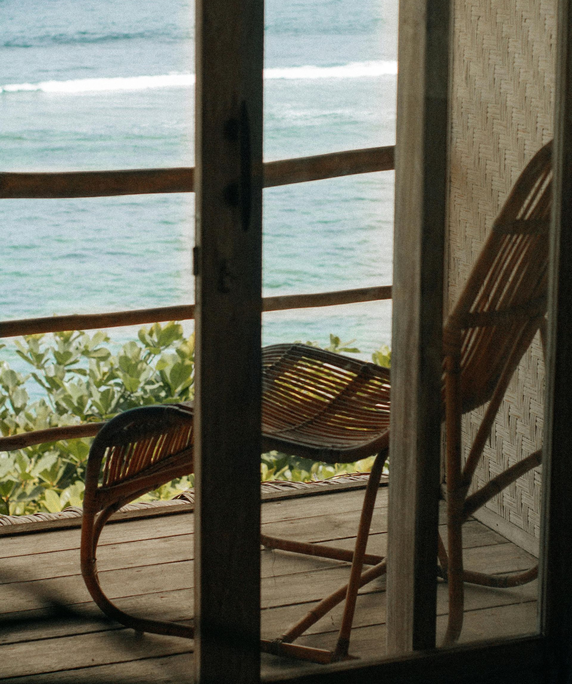 Ocean view from balcony with wicker chair.