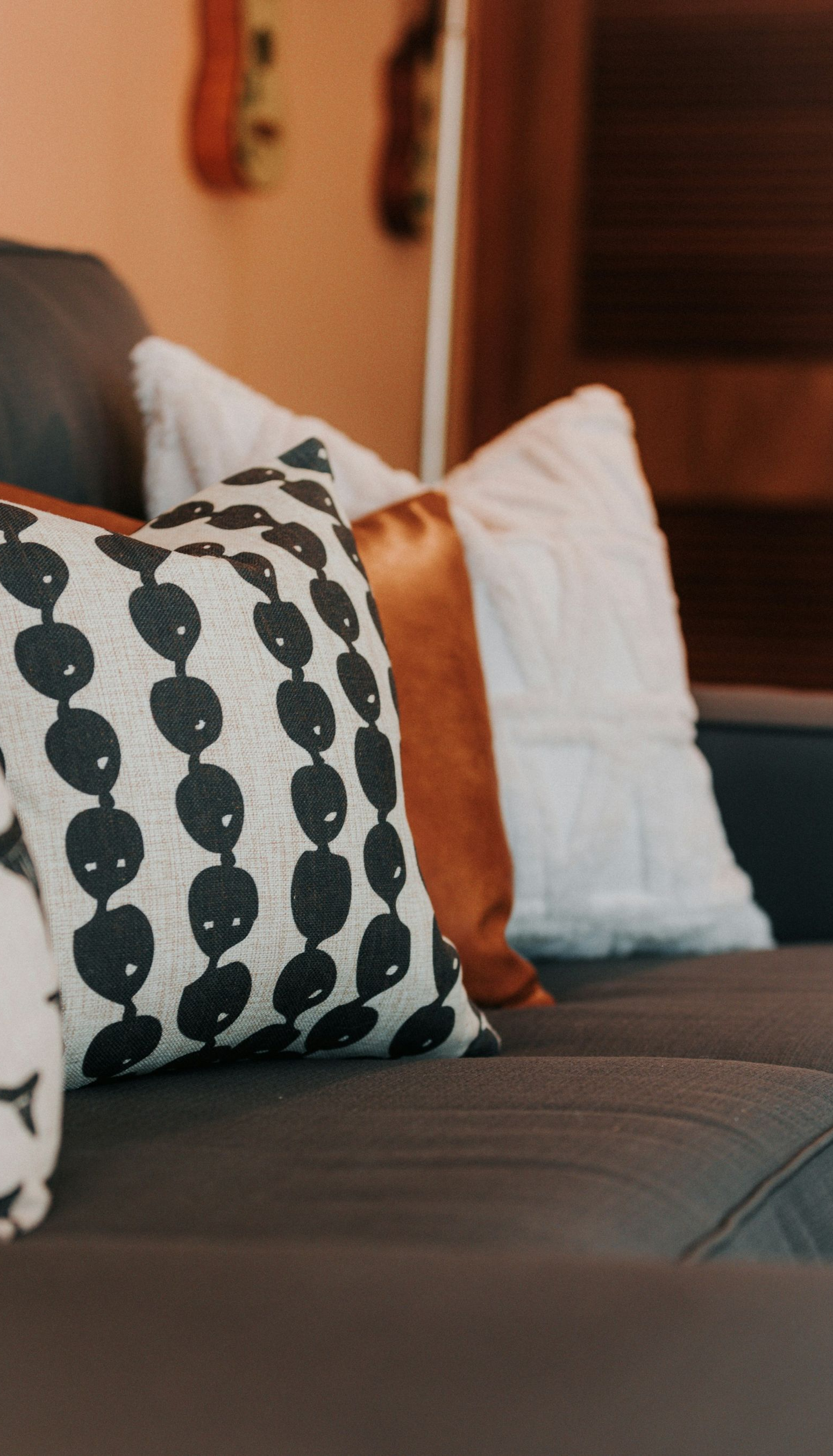 A dark gray couch featuring several decorative pillows in patterns of black and white, tan, and plain white.