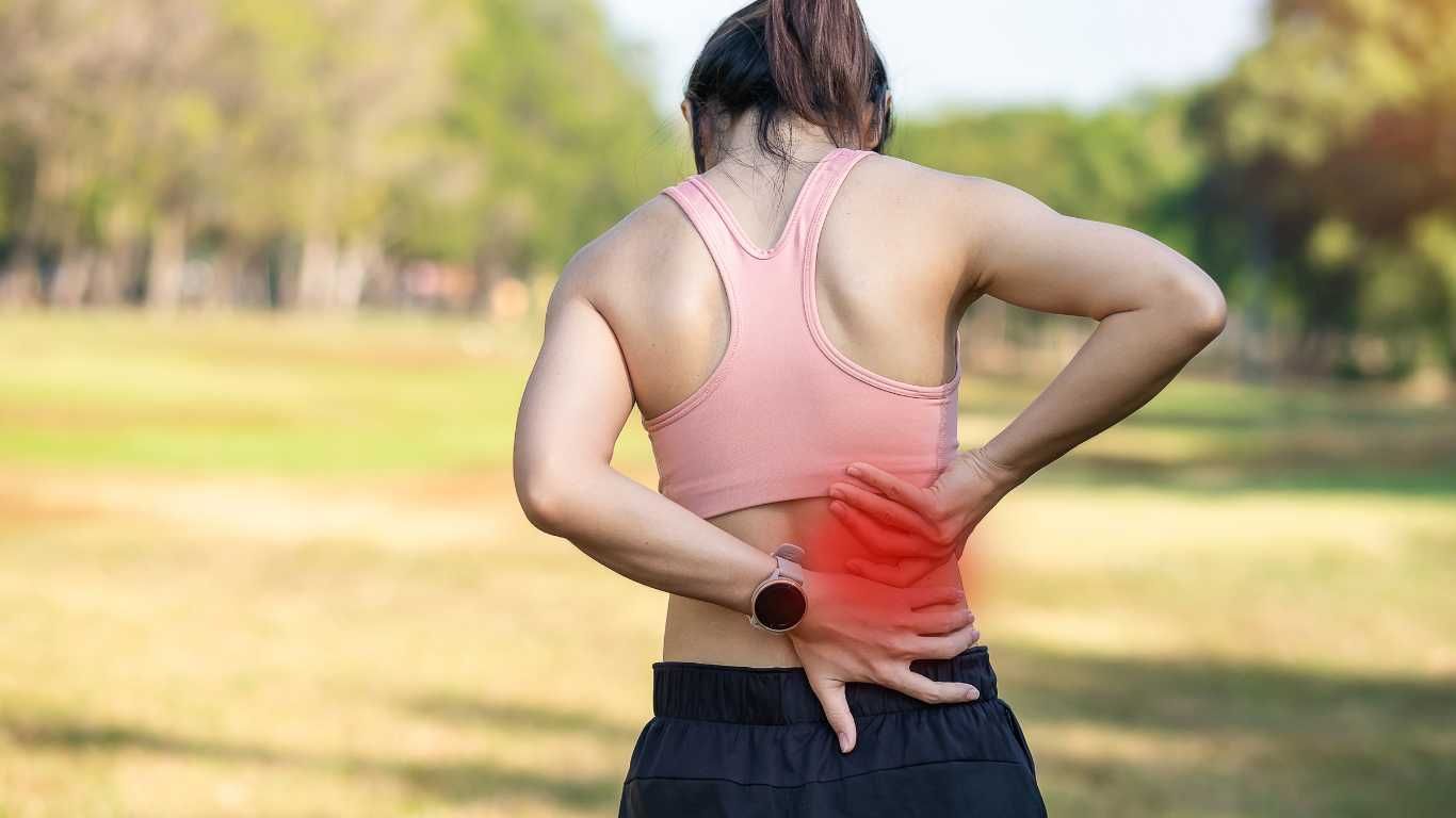 A person applying a heat pack to their lower back for pain relief