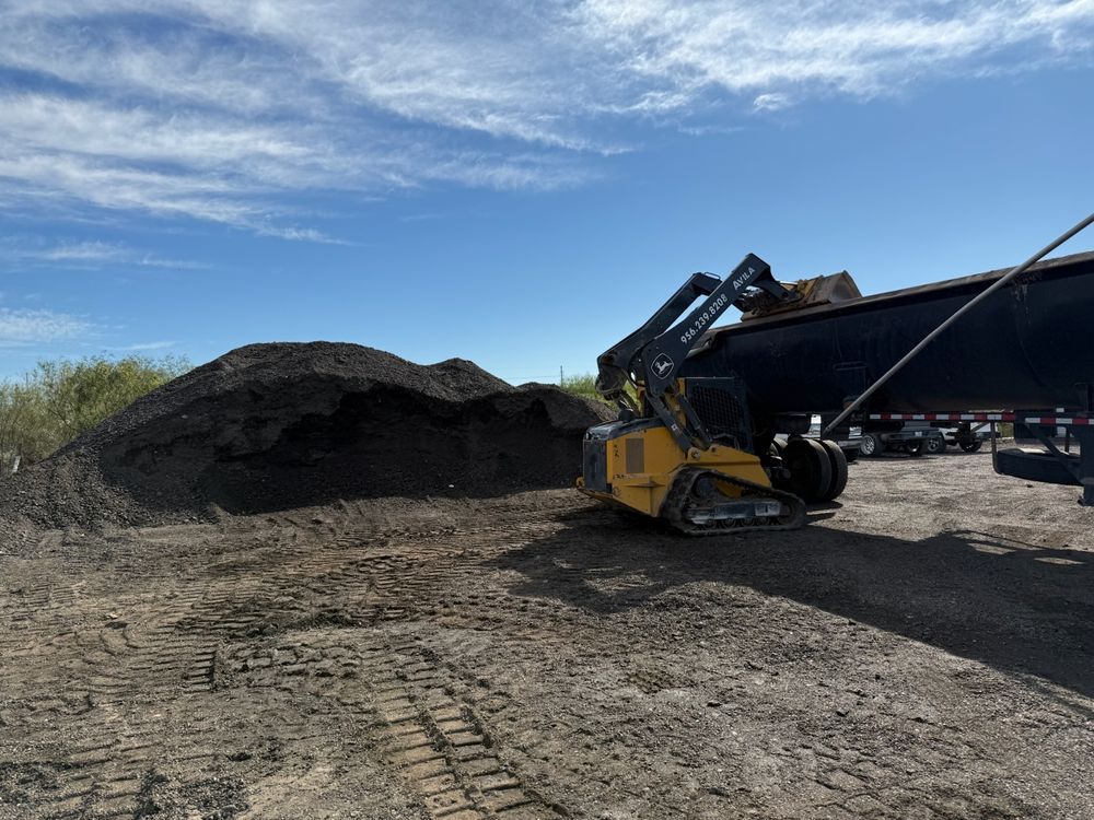 A trackloader loading dirt into a dump truck on a job site near Edinburg, Texas.