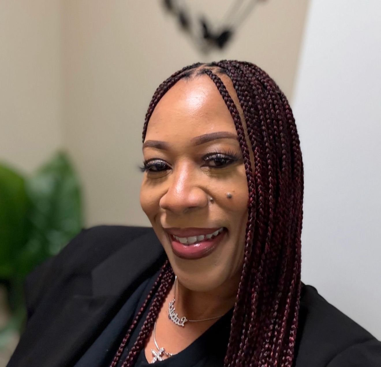 A woman with braids is smiling and wearing a black jacket