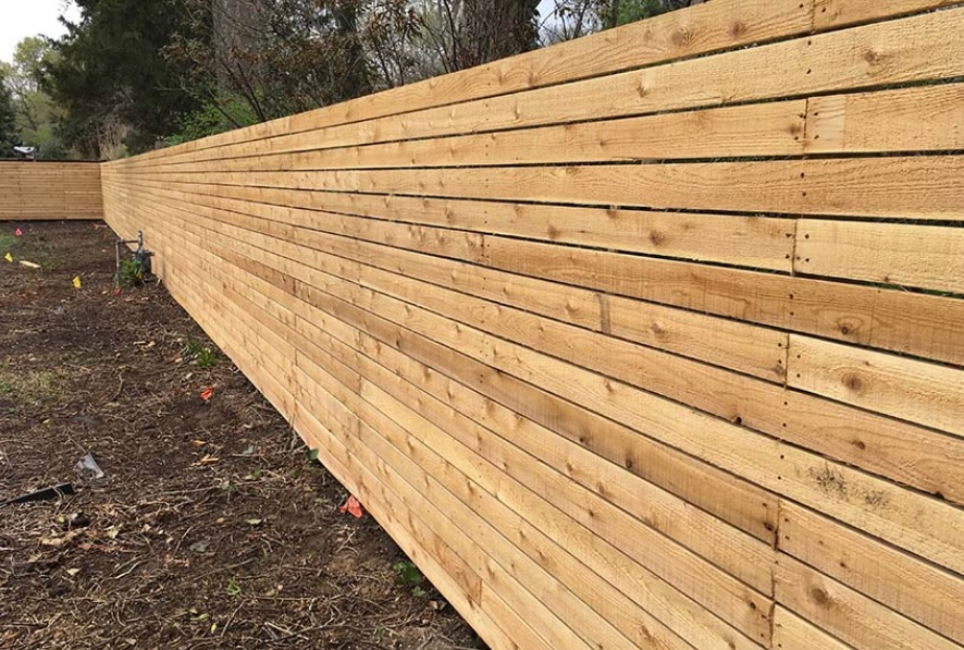 Wooden horizontal plank fence in an outdoor setting.