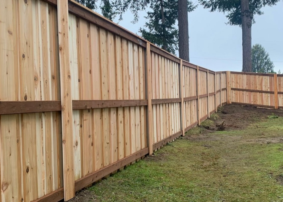 Wooden privacy fence in a grassy yard, under an overcast sky.