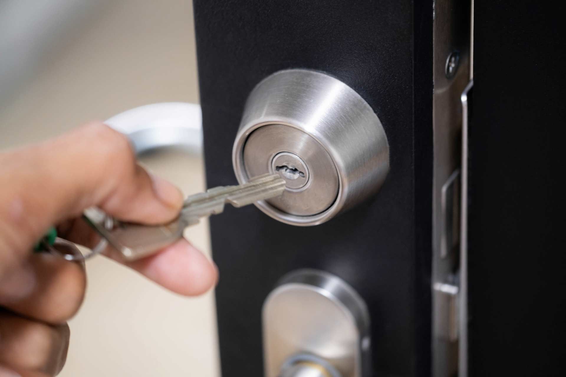 A person is holding a key in a door lock.