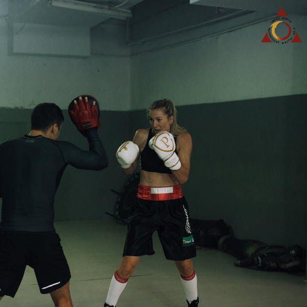A man and a woman are practicing boxing in a gym