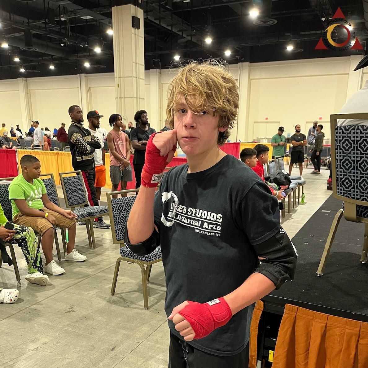 A young man wearing boxing gloves and a black shirt with the word studios on it