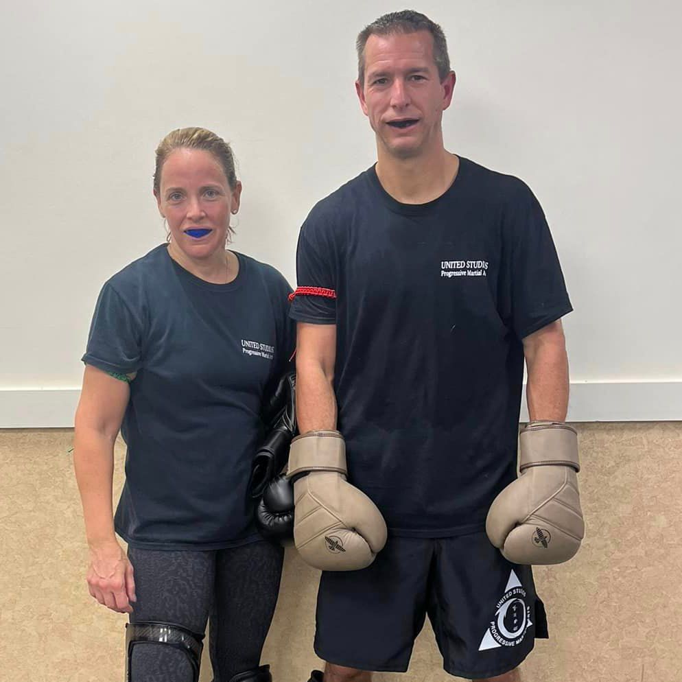 A man and a woman are standing next to each other wearing boxing gloves.