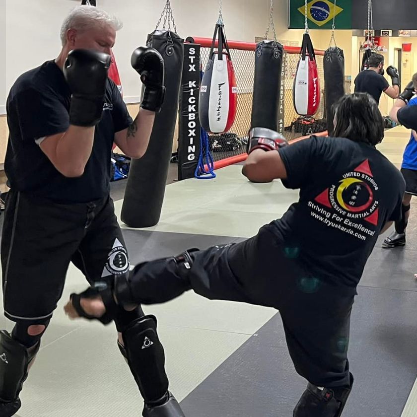 Two men are kickboxing in a gym with a flag in the background