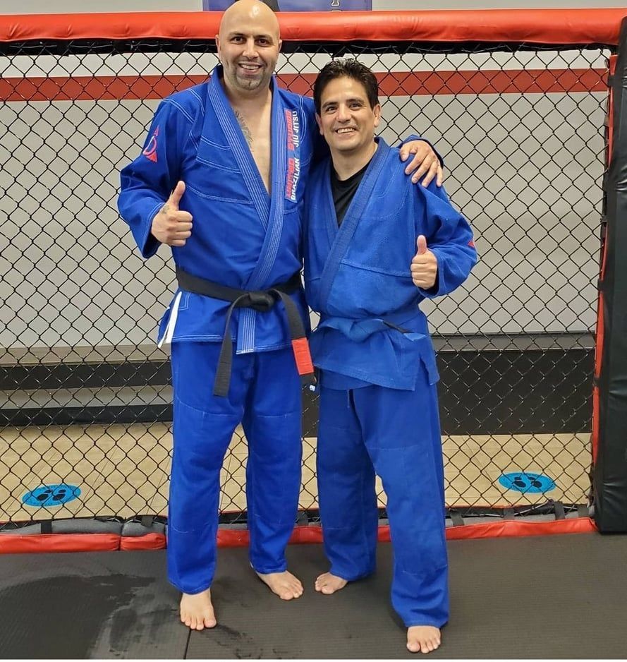 Two men in blue karate uniforms are posing for a picture