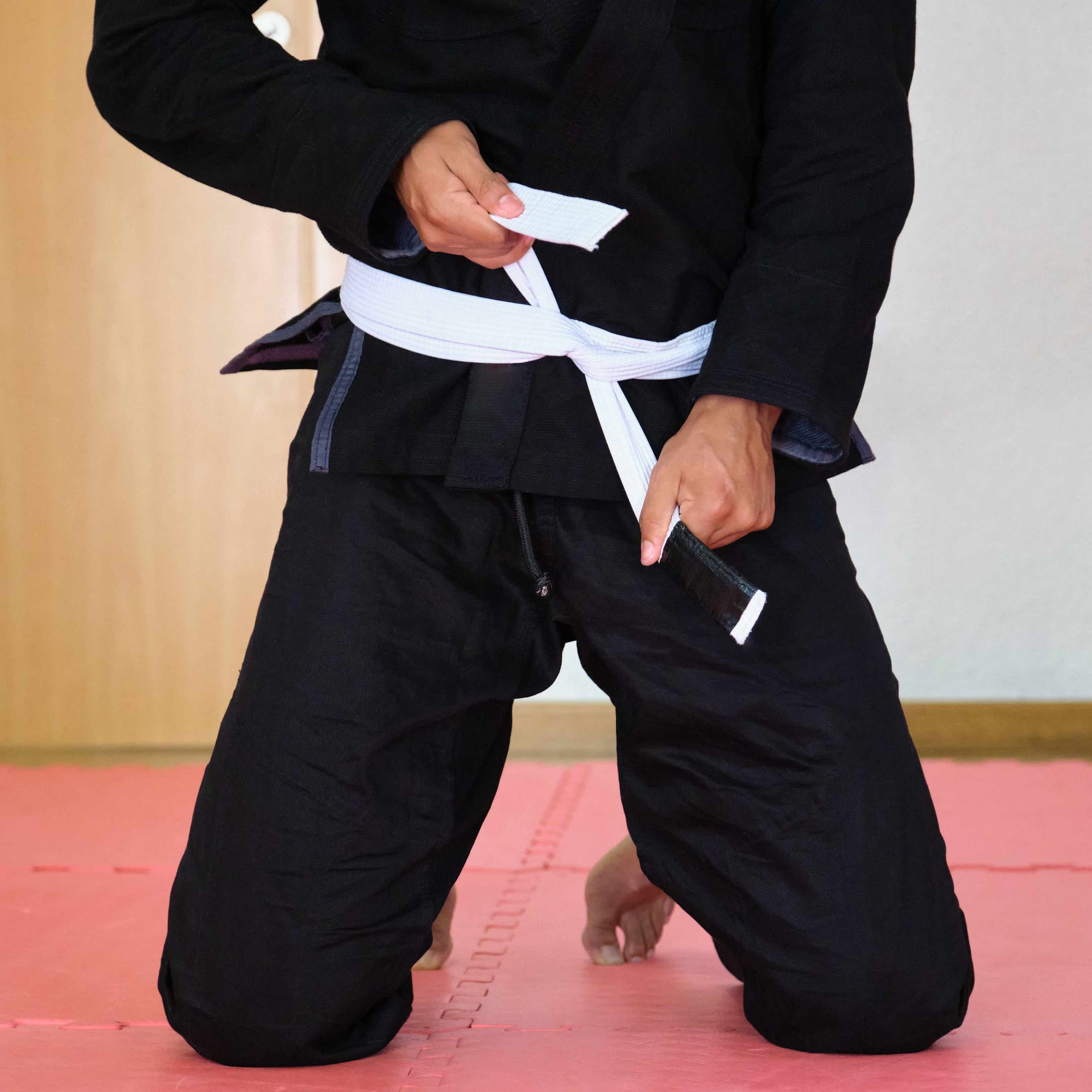 A man in a black karate uniform has a white belt around his waist