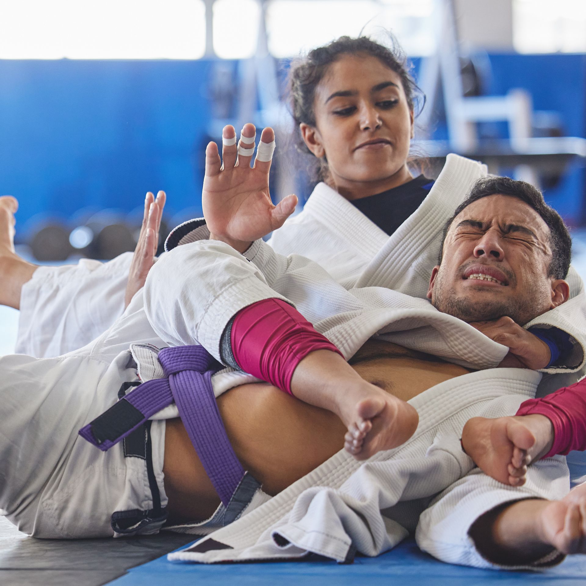 A man and a woman are wrestling in a gym.