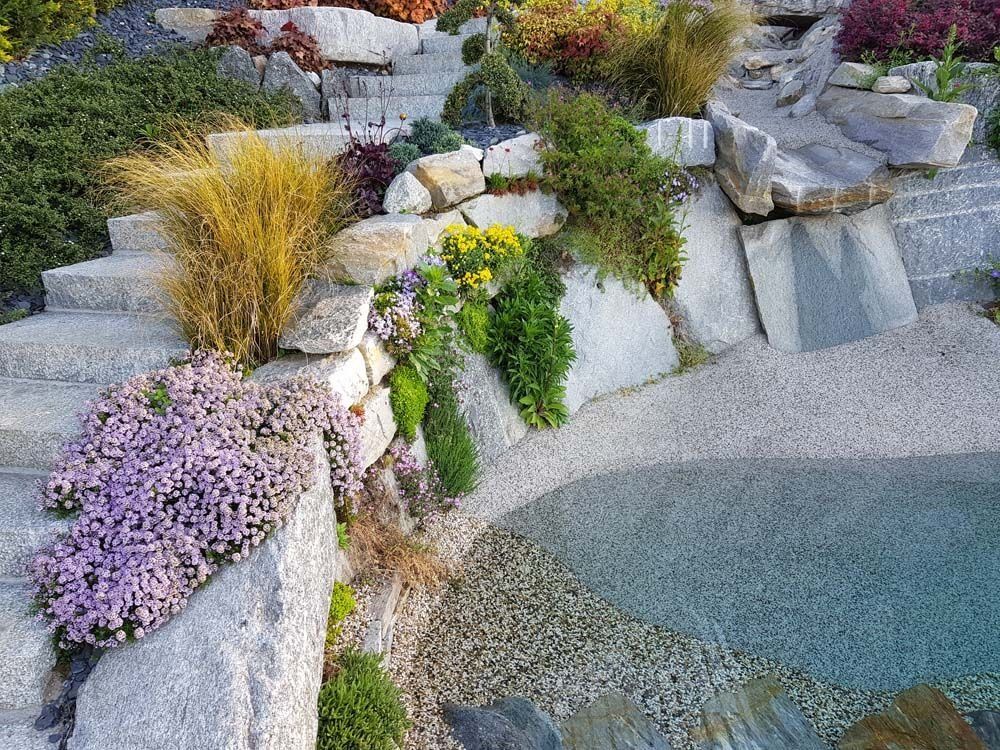 Gradini in pietra con piante colorate e piccolo laghetto.