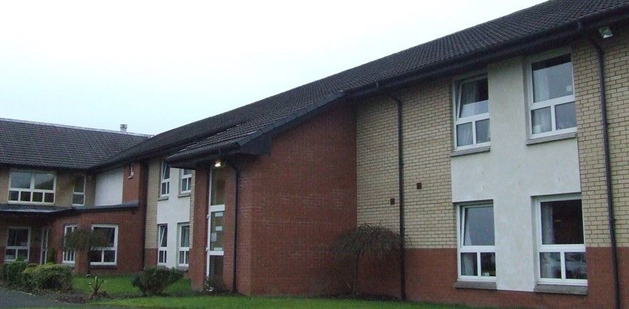 Building with a dark roof and brick exterior under a cloudy sky.