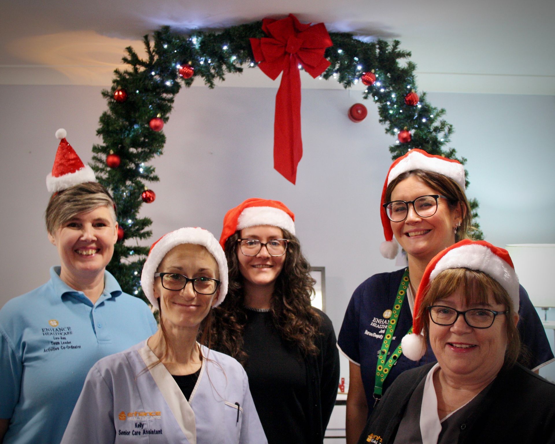 A group of women wearing santa hats are posing for a picture