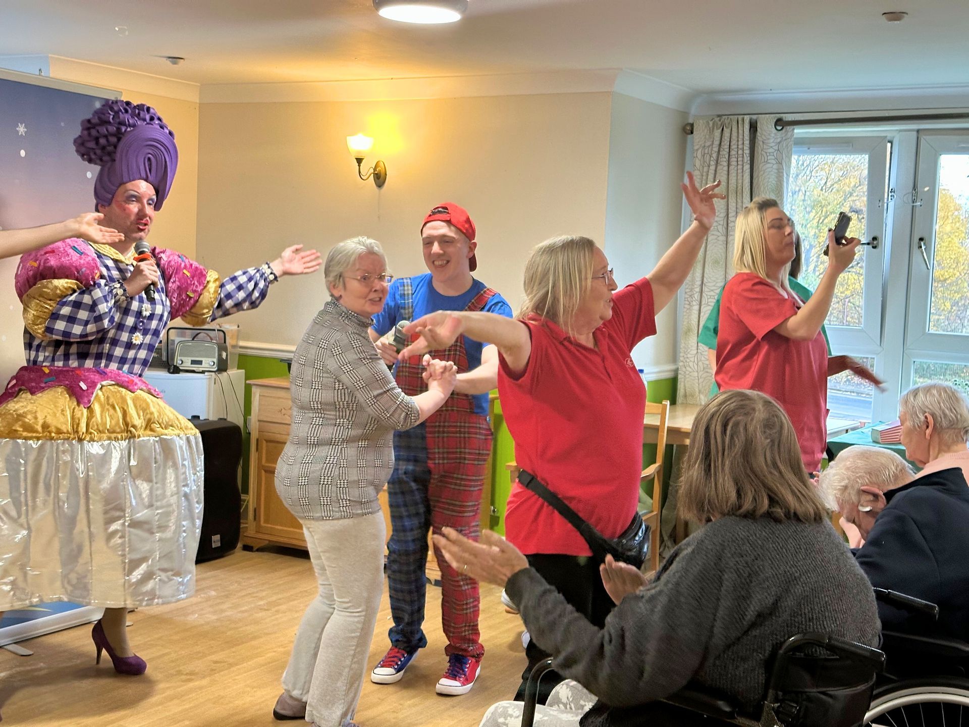 A performance in a room with a performer in a costume and audience members dancing.