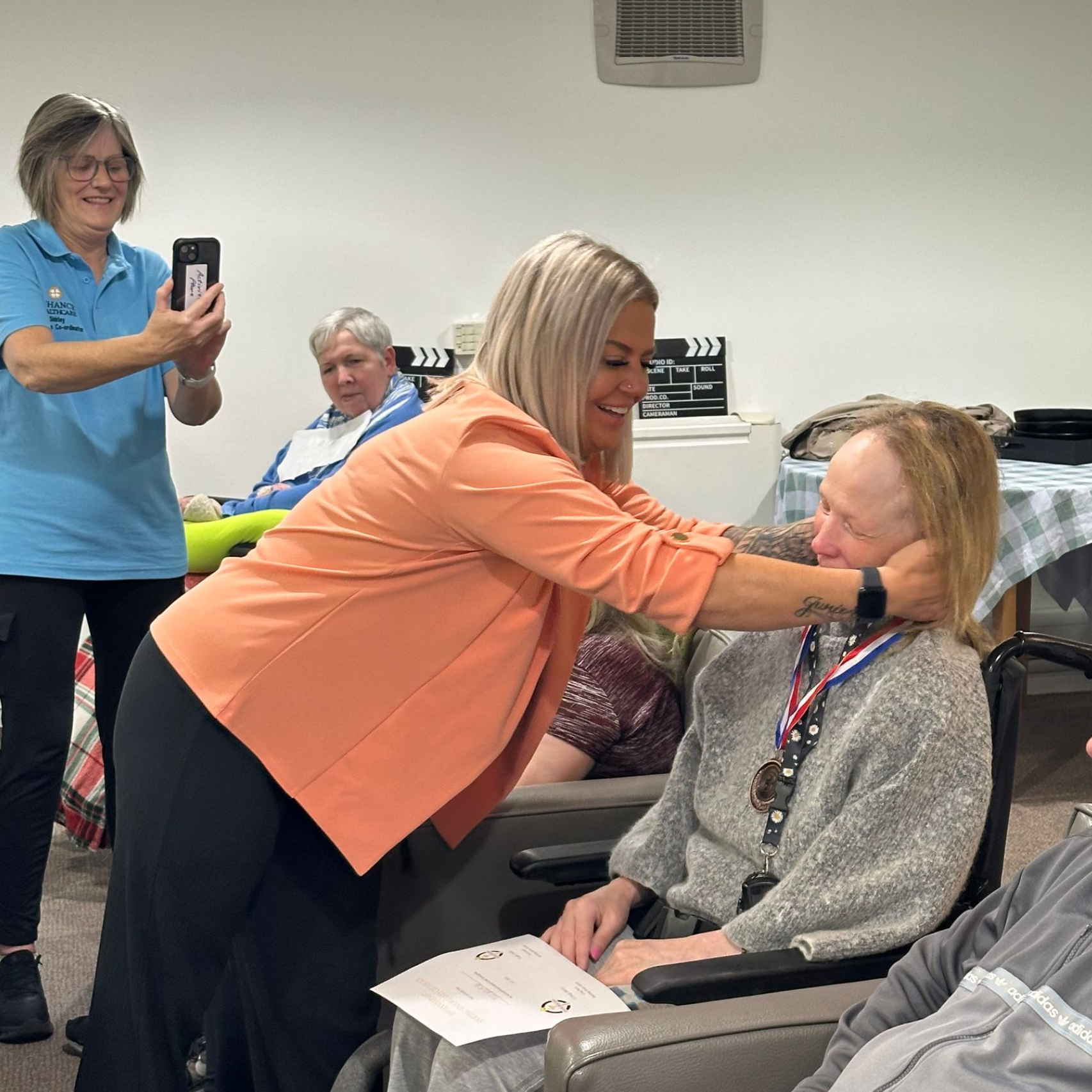 Woman presenting a medal to another woman in a wheelchair