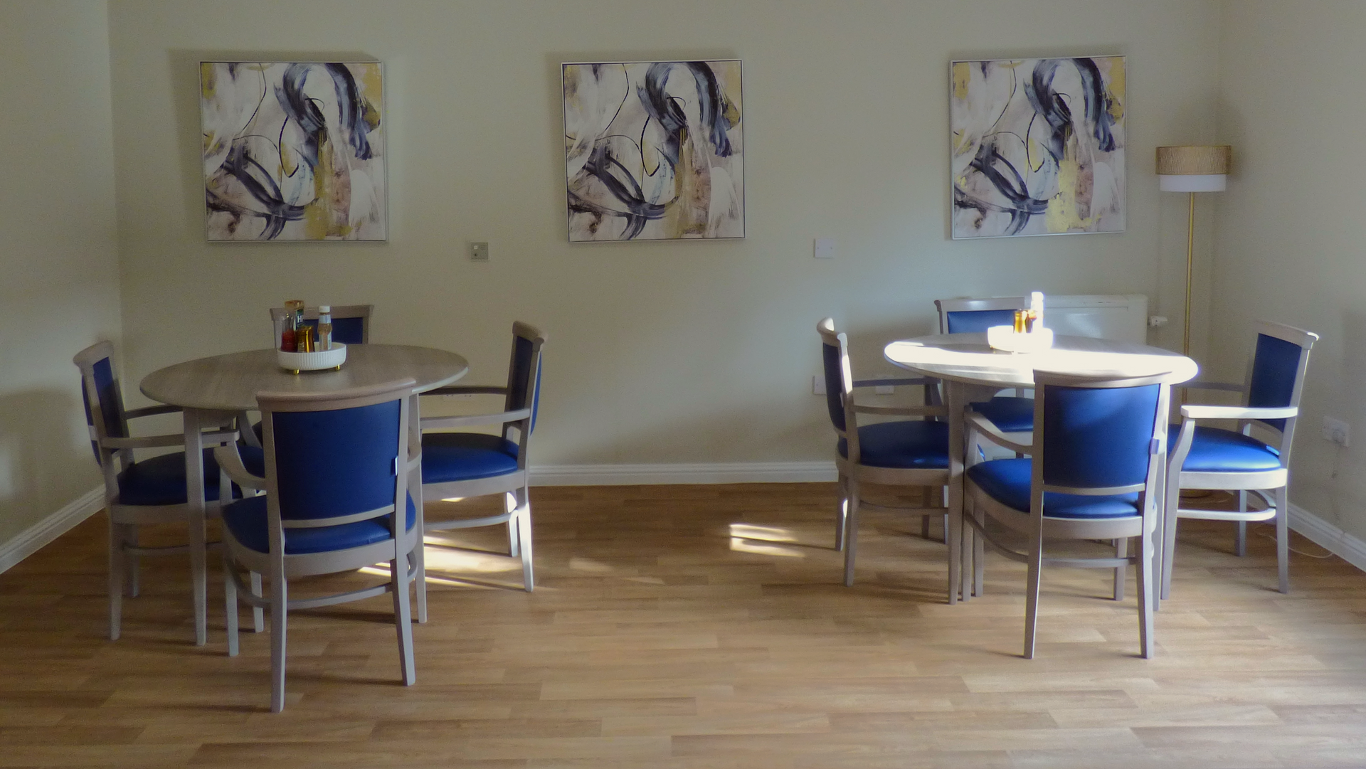 A dining room with a table and chairs and paintings on the wall.