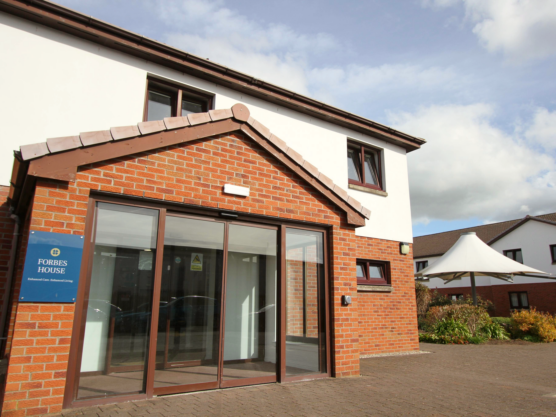 A brick building with a blue sign that says ' Forbes House ' on it