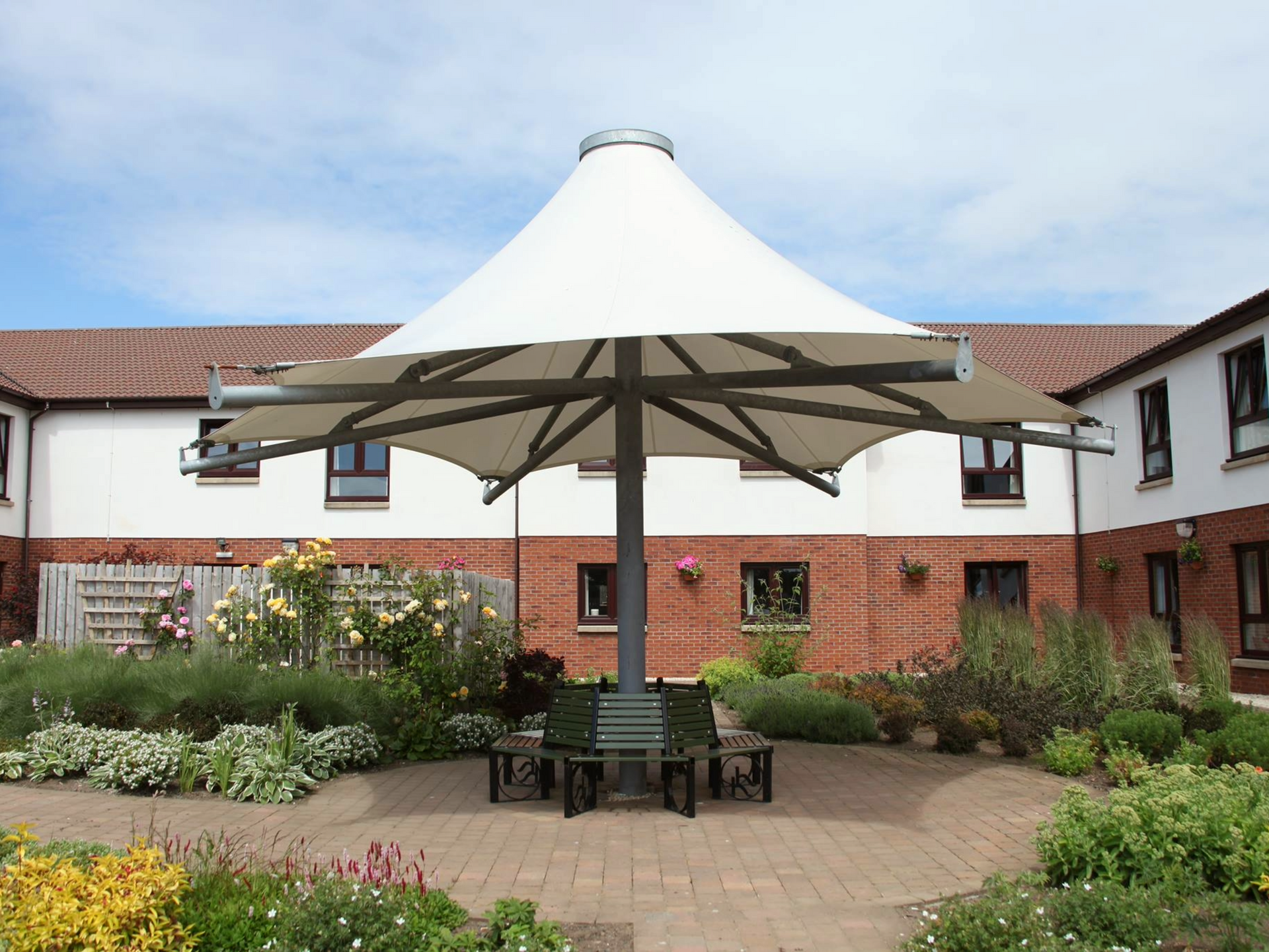 A large white umbrella is in the middle of a garden