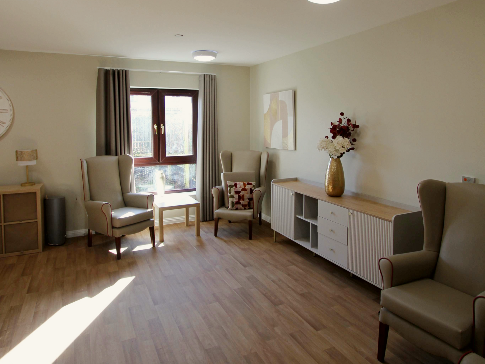 A living room with chairs and a clock on the wall.