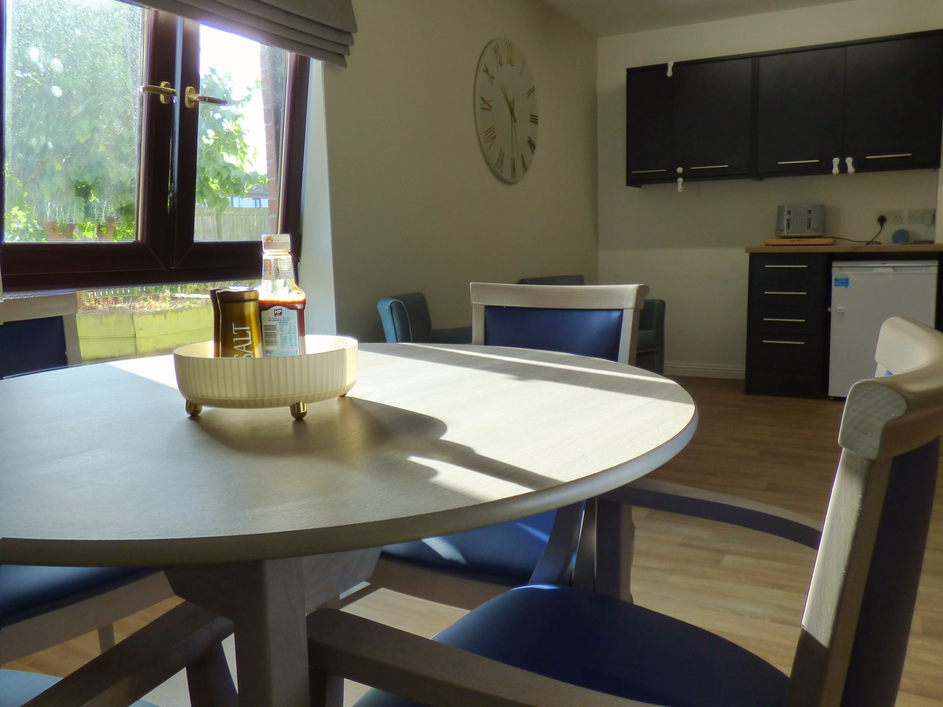 A kitchen with a round table and chairs and a clock on the wall