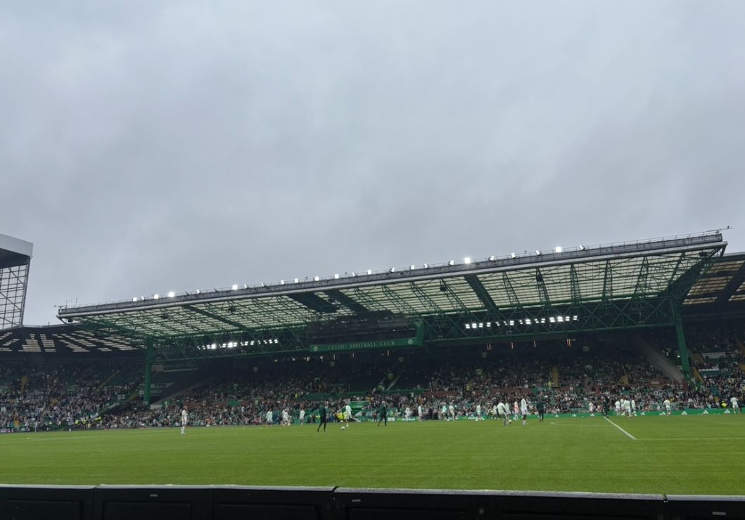 Large stadium filled with people watching a soccer game on a cloudy day. 