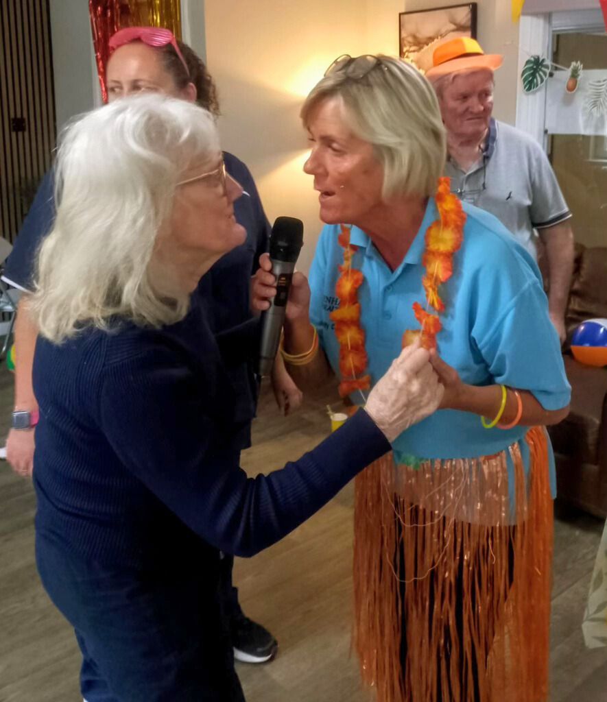A woman in a blue shirt is talking into a microphone