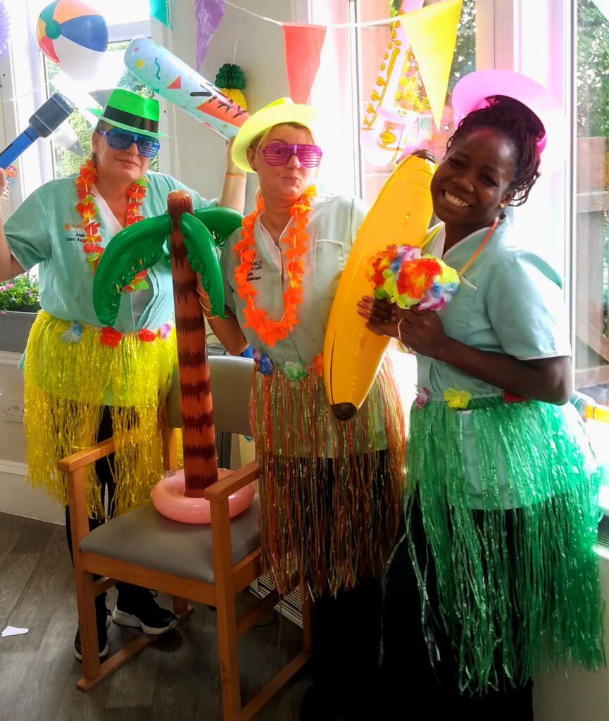 Three women dressed in hawaiian costumes are posing for a picture