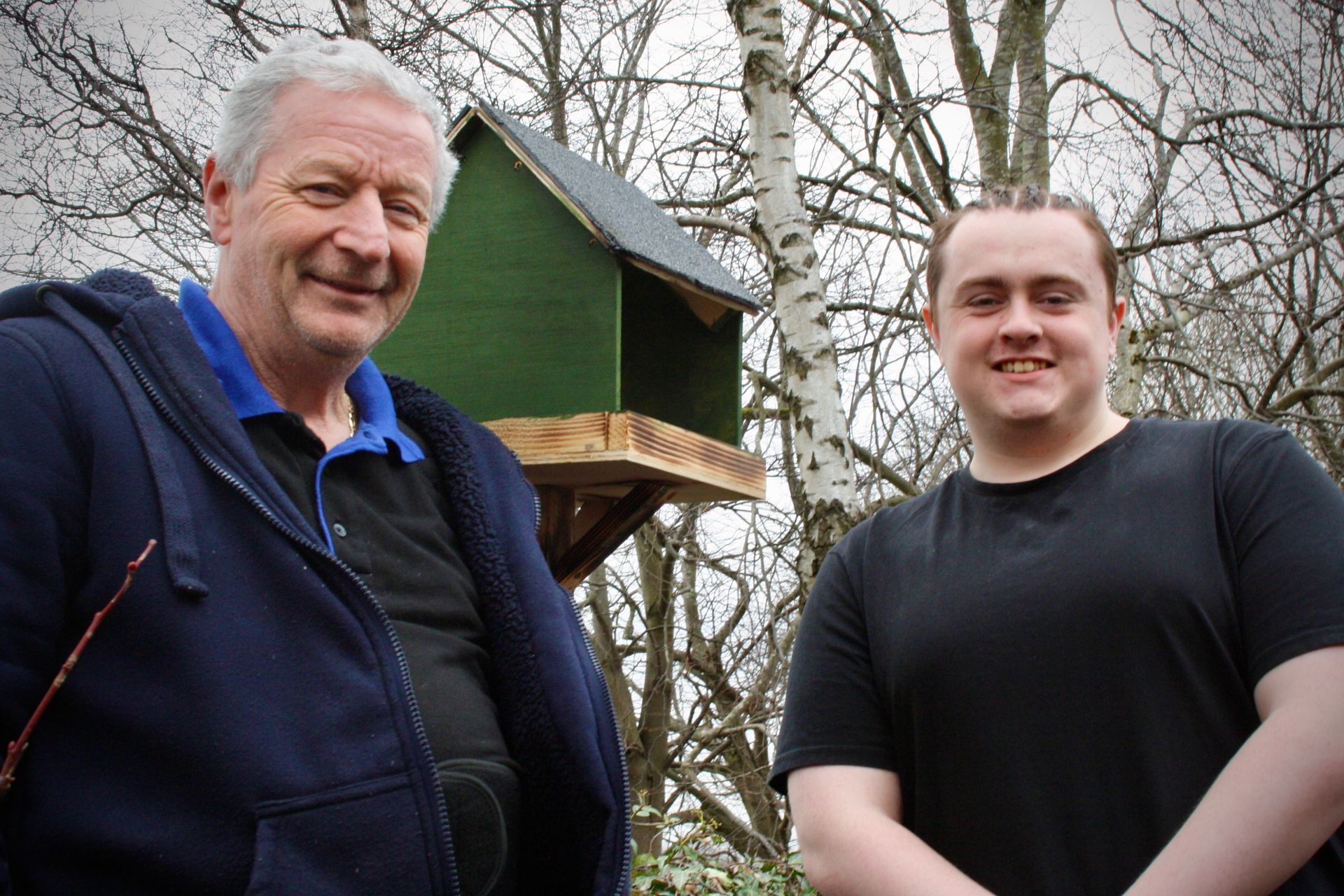 two people standing next to a birdhouse