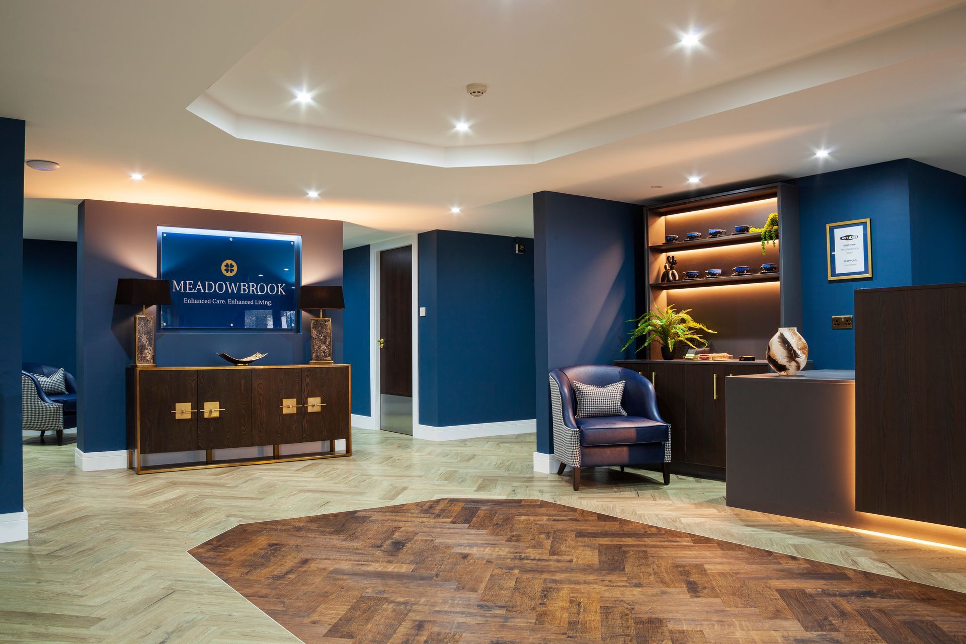 Living room with TV, beige walls, armchairs, and wood flooring.