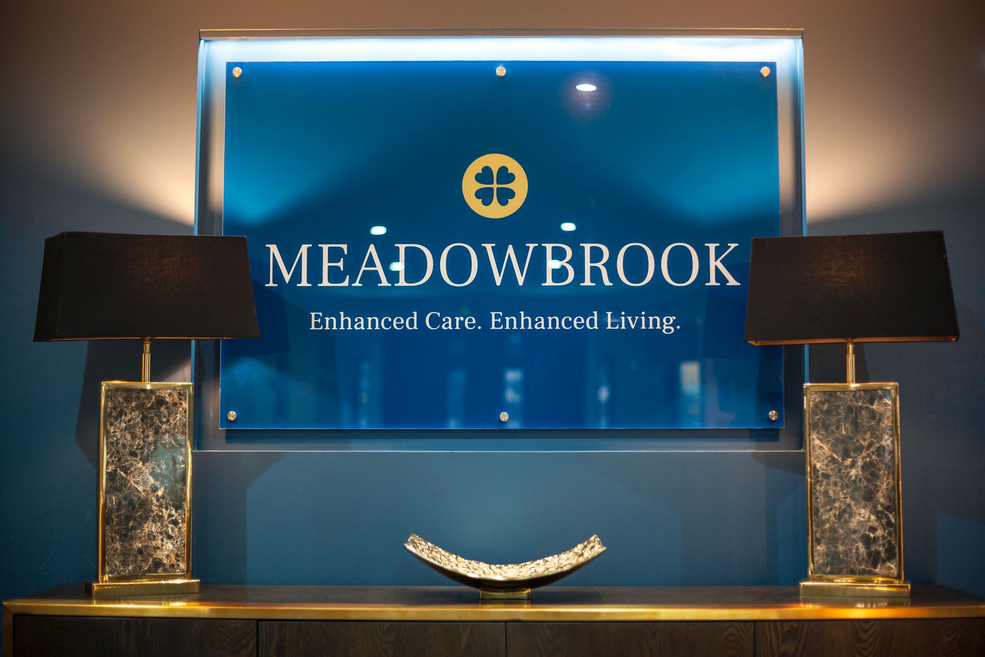 Red brick building with awning over entrance, green supports, windows, and small bushes.