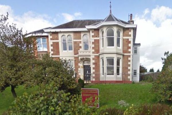 A large brick house with a sign in front of it