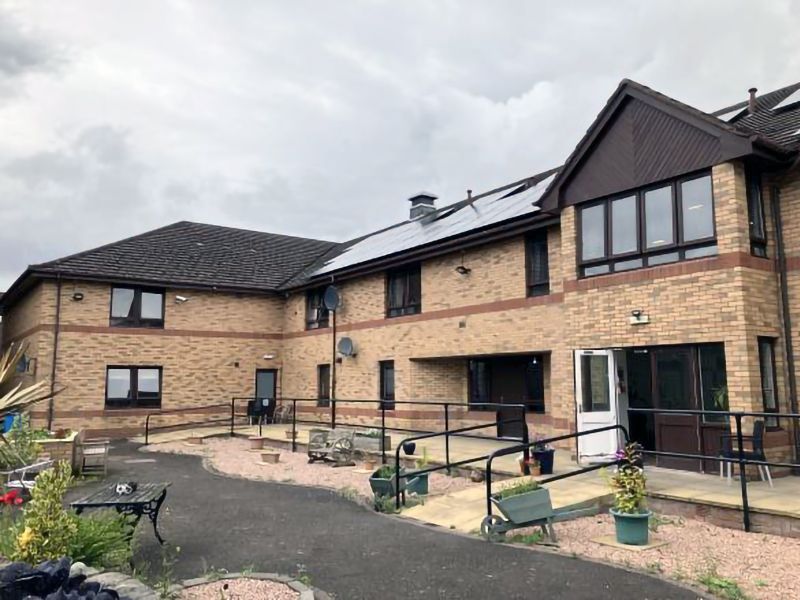 Two-story brick building with solar panels on roof and ramp for accessibility.