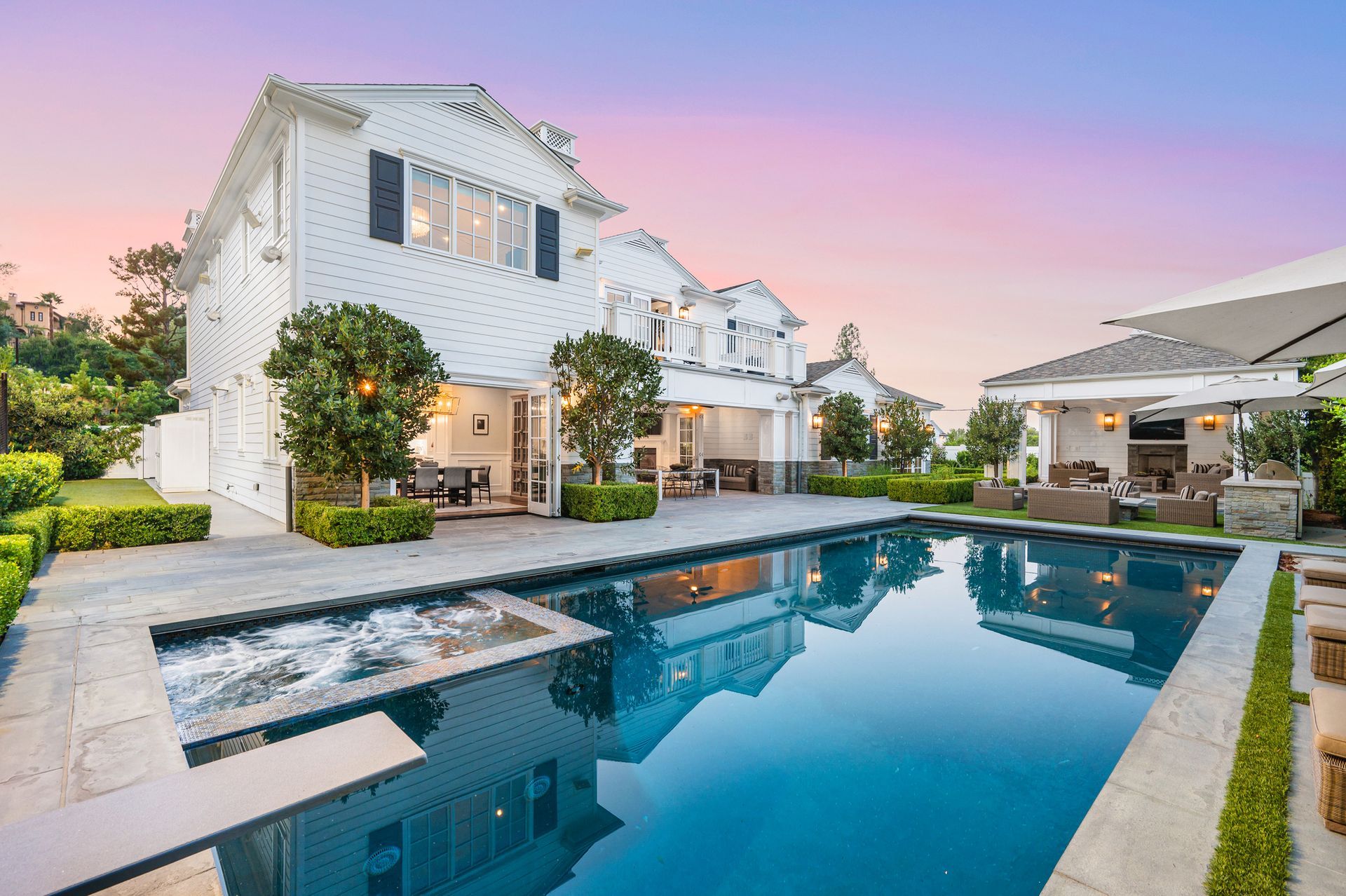 Luxury home with pool, hot tub, and outdoor lounge at sunset.